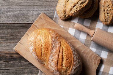 Doğrama tahtasının üzerinde taze pişmiş ekmek kepekli çörekler ve yanında merdane. Her şeyi ahşap masaya koyun. Fırın, fırın konsepti.