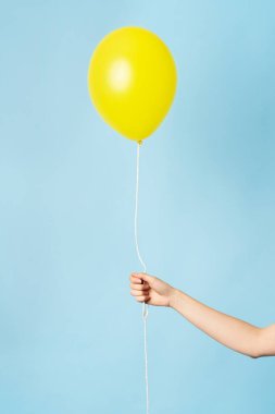Bir kadının elinde havada süzülen sarı balon. Sarı 