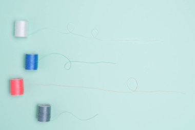 Yeşil arkaplanda renkli iplik makaraları, dikiş 