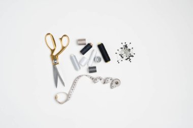 Sewing accesories scattered all over the white background. 