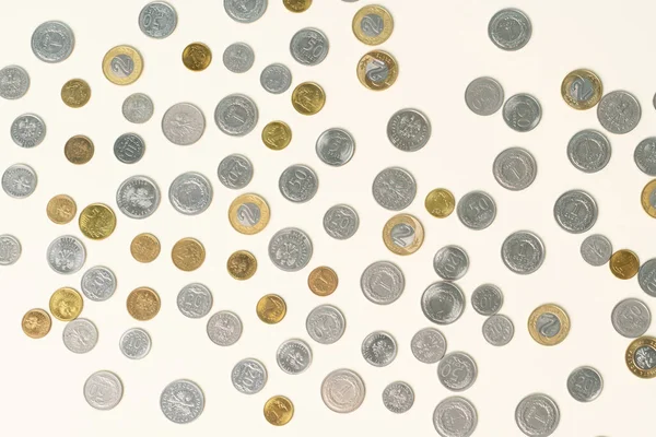 A lot of silver and gold coins scattered all over the beige