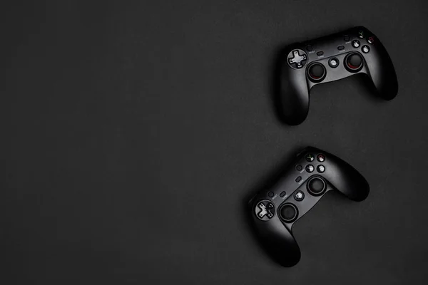 Two black wireless game pads on the black background.