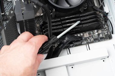 Hands of computer engineer repairing a modern desktop computer with screwdriver. Technolocy concept.