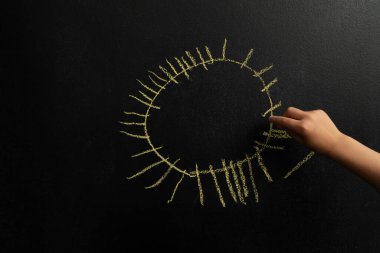 Siyah tebeşir tahtasına resim çizen küçük bir çocuk resmi.. 