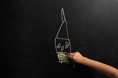 Siyah tebeşir tahtasına resim çizen küçük bir çocuk resmi.. 