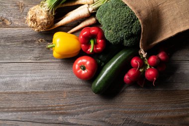 Biz domatesler, turplar, maydanoz, brokoli ve biber gibi taze sebzeler marketten alınıp tekrar kullanılabilir eko alışveriş poşetine konur. Her şey eski ahşap masada ortaya çıkar..