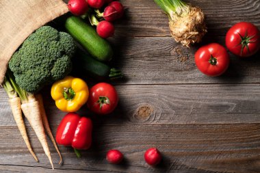 Biz domatesler, turplar, maydanoz, brokoli ve biber gibi taze sebzeler marketten alınıp tekrar kullanılabilir eko alışveriş poşetine konur. Her şey eski ahşap masada ortaya çıkar..