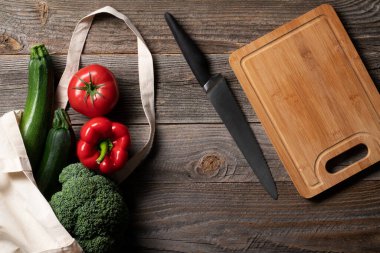 Tekrar kullanılabilir alışveriş torbasında taze sebzeler, marketten toplanıp doğranacak tahtalara kadar uzanıyor. Salata yapmaya hazırım. Her şey eski ahşap masada ortaya çıkar.
