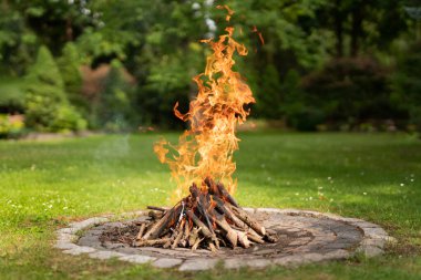Beautiful bonfire burns in the middle of the garden during the day.