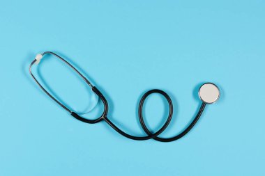 Black stethoscope, top view on  the blue background. Medical equipment, tool for measuring the heart rate, lungs, and abdomen sounds