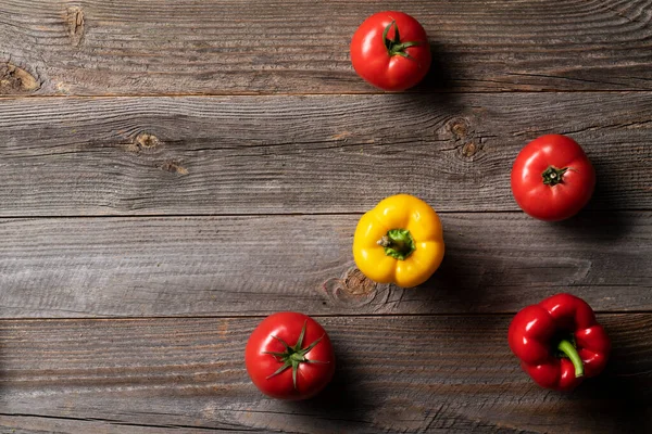 Taze domates, kırmızı ve sarı biber eski ahşap masada sergileniyor. Frocery çiftliği alışverişi. Mutfak konsepti.