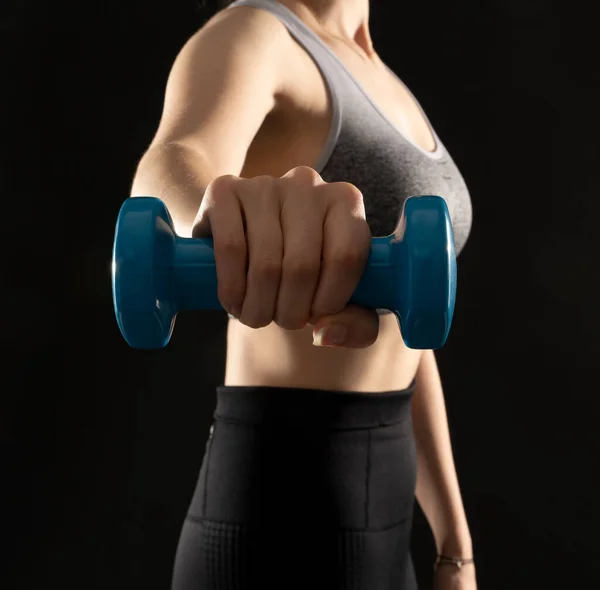 Close up photo of healthy woman working out with dumbbells on the black background