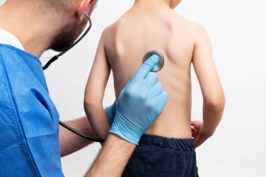 Close up picture of doctor examining a little bou with stethoskope. Boy went to rutinal doctor's check up. Health care concept.