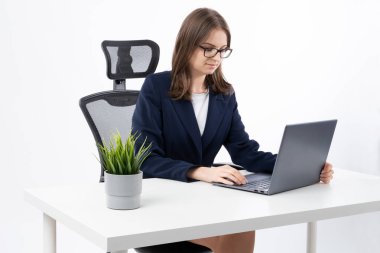 Young and happy bussines woman working on her computer in her work office. Motivated and succesfull womand solving problems and looking for solutions.