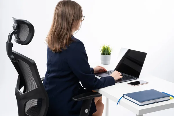 Young caucasian bussines woman working on her computer. Office desktop, notebook and flower on white dress.