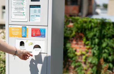 Woman taking her parking ticket from the parking meter in the street of big city. 