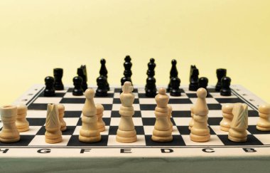 Chess pieces in the playing position on the wooden chess board.