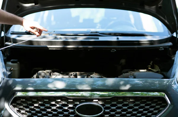 Man checking th engine oil level  at the parking. Regular car 