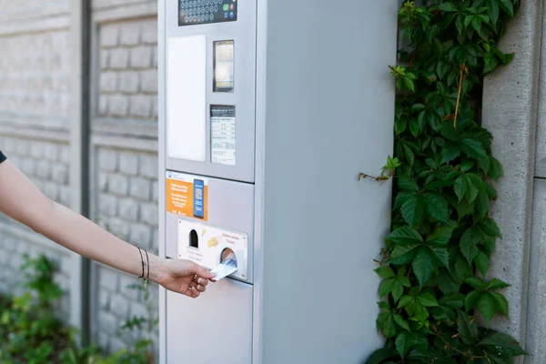 Woman taking her parking ticket from the parking meter in the street of big city. 