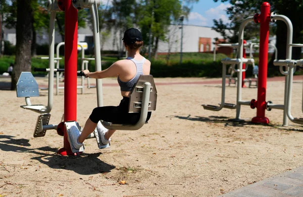 Young athletic woman performing excercises in an outdoor gym. 