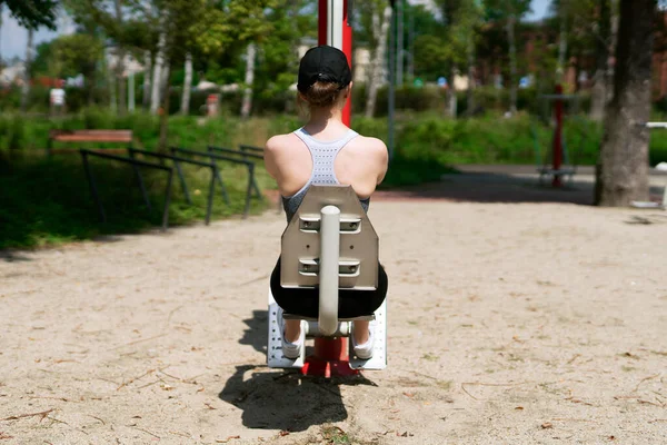 Young athletic woman performing excercises in an outdoor gym. 