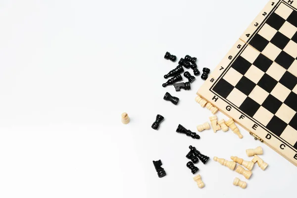 stock image Top view of wooden chess board and chess pieces scattered on the white background. 