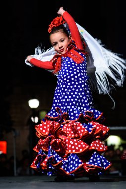 Geleneksel kostümlü küçük kız sahnede İspanyol flamenko dansı yapıyor..
