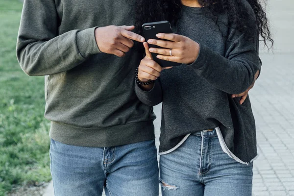 Casal jovem visualizando conteúdo em um telefone celular enquanto caminham juntos ao ar livre na rua. — Fotografia de Stock