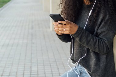 Sokakta kullanırken cep telefonunda daktilo eden bir kadının yakın görüntüsü.