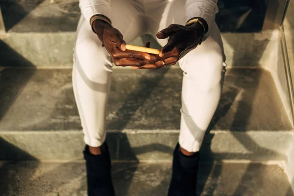 Close up view of a woman using a mobile phone while sitting on stairs.