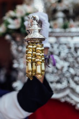 A hand holding a detail of a pomegranate Easter virgin. Easter procession in Granada.