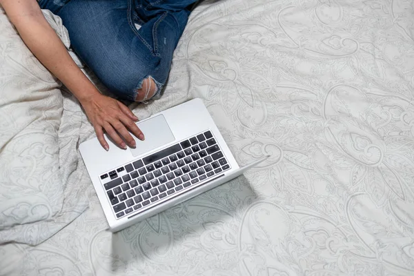 Mujer usando un ordenador portátil mientras está sentado en la cama. —  Fotos de Stock