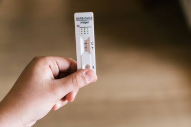 Bir kişi elinde pozitif bir covid-19 antijen testi tutuyor. Ev Hızlı Testi.