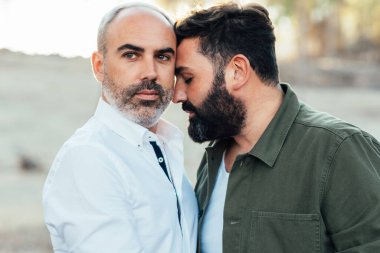 Açık havada eğlenirken birbirine yakın duran eşcinsel erkek çift..