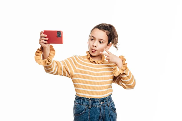 Νεαρό κορίτσι κολλήσει γλώσσα έξω και να κάνει την ειρήνη σημάδι με τα δάχτυλα, ενώ λαμβάνοντας μια selfie με ένα κινητό τηλέφωνο. — Φωτογραφία Αρχείου