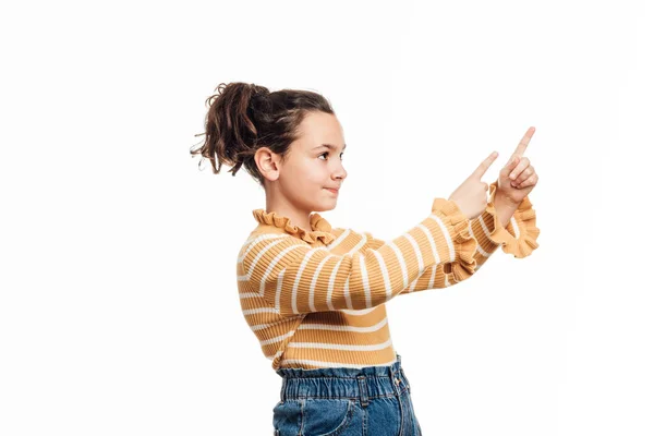 Młoda dziewczyna wskazując w bok, aby pokazać coś stojąc na odosobnionym tle. — Zdjęcie stockowe