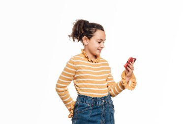 İzole edilmiş beyaz bir arka planda dururken cep telefonuyla video görüşmesi yapan genç bir kız..