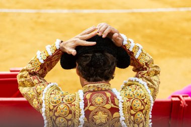 Boğa güreşçisi Montera 'yı ya da boğa güreşi şapkasını elleriyle takıyor..