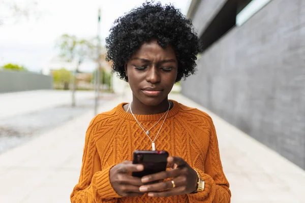 Jovem Afro Mulher Parece Confuso Enquanto Assiste Algo Seu Telefone — Fotografia de Stock