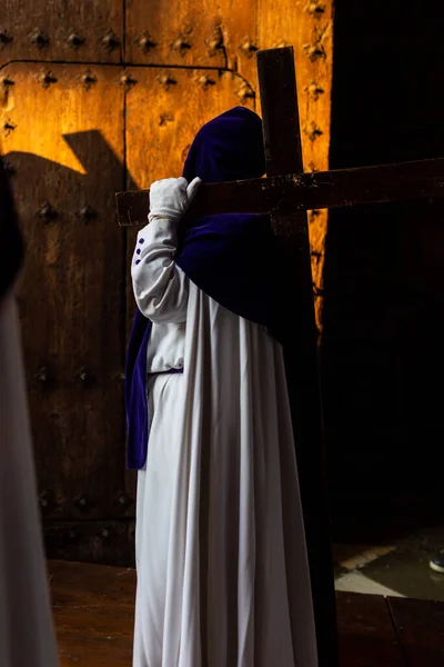 Holy week celebration in spain, andaucia,granada. unrecognizable person in a nazarene habit carrying a cross on his back in a procession of faith. — Stock Photo, Image