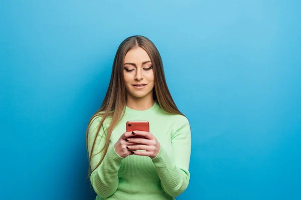 Žena pomocí mobilního telefonu, zatímco stojí nad izolovaným pozadím. — Stock fotografie