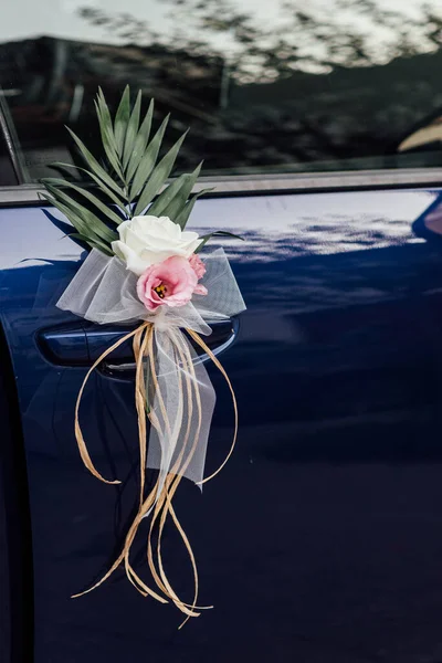 Close up view of a wedding car with a flower decoration on the door. Newlyweds car. Wedding and transport concept.