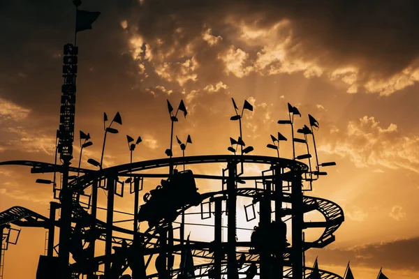 Silhouette of a roller coaster in an amusement park during sunset. Entertainment and fun concept.