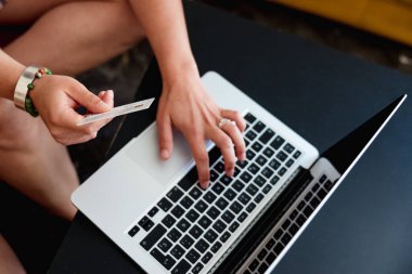 Close up view of woman using laptop and credit card while shopping online at home. Online shopping and e-commerce concept.