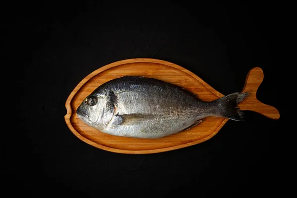 Roh Frischer Dorado Fisch Holzteller Fischform Auf Schwarzem Tisch Draufsicht — Stockfoto