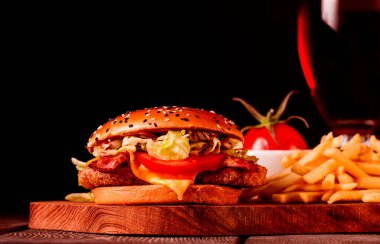 Tavuk pirzolası, kızarmış domuz pastırması ve sebzeli hamburger, patates kızartması, bir bardak bira, ahşap tahtada, insan yok, yatay.,