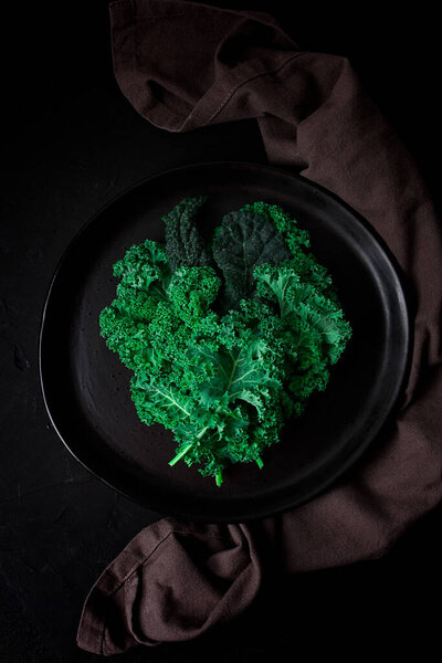 Food background, on a black table, top view, Fresh Kale leaves, close-up, vertical , no people, toned. selective focus,