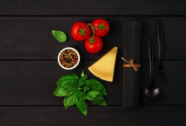 Kavram, bir buket siyah makarna, çiğ, siyah ahşap bir masa üzerinde, malzemeler ve çatal bıçak takımı, üst görünüm, yatay, insan yok.,