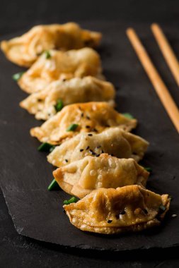 Japon Gyoza köfteleri, kızarmış, soslu, siyah arka planda, üst tarafta, insan yok, tonlu, haşlanmış, seçici odaklı.