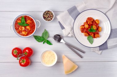 İtalyan yemeği, domates soslu gnocchi, fesleğen, patates köftesi, beyaz ahşap bir masada, insan yok, üst manzara, Yüksek kalite fotoğraf